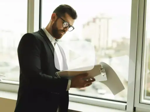 Hombre con gafas revisa documentos. Explica qué es un aval bancario para alquiler, una garantía para el arrendador.