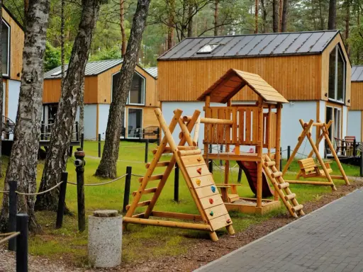 Drewniany plac zabaw z domkami w tle – idealne bory tucholskie atrakcje dla dzieci.