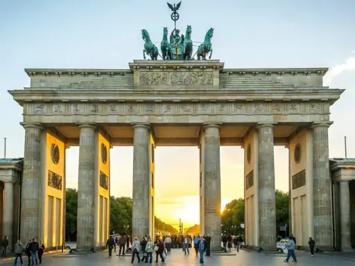 Brandenburger Tor i Berlin, en ikonisk sevärdhet som visar vad man ska se i Berlin. Solnedgången lyser upp monumentet och folklivet.