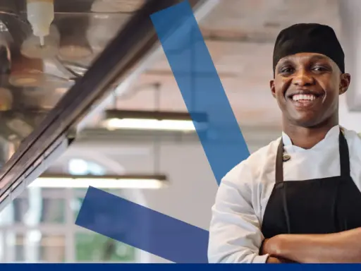Chef sonriente en cocina profesional, ideal para la seleccion personal hosteleria.