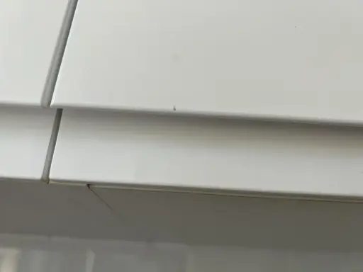 Detalle de un mueble lacado blanco con pequeños arañazos, listo para reparar.