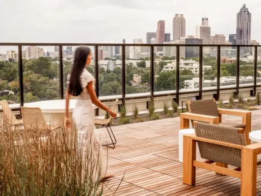 Frauen auf einer Dachterrasse mit Blick auf eine Stadt der kurzen Wege. Moderne Möbel laden zum Verweilen ein.