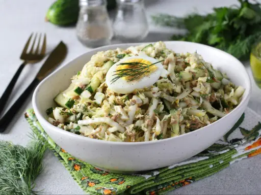 Lekka sałatka z tuńczykiem, jajkiem i ogórkiem, udekorowana koperkiem. Idealna na szybki lunch.
