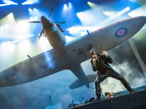 Bruce Dickinson sjunger framför ett Spitfire-plan under Iron Maiden Ullevi. Scenen är fylld av rök och ljus.