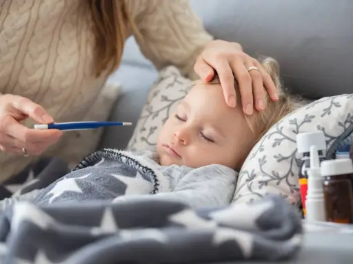 Matka mierzy gorączkę śpiącemu dziecku, troskliwa opieka nad zdrowym dzieckiem, gdy jest chore.
