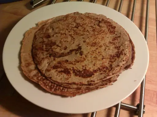 En hög med tunna pannkakor på en vit tallrik. Perfekt för en mysig frukost eller som frukost tips.