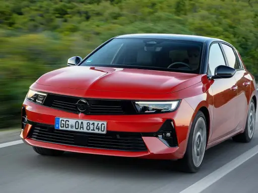 El nuevo Opel Astra rojo, con techo negro, circula por una carretera sinuosa rodeada de vegetación.