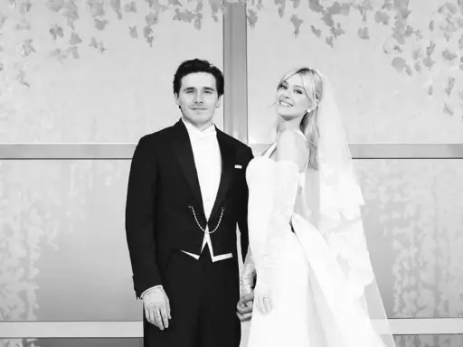 Novios sonrientes en la boda Brooklyn Beckham. Él con esmoquin, ella con velo y vestido blanco.
