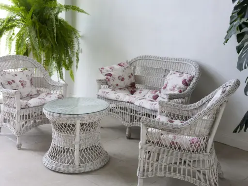 Conjunto de muebles de mimbre blanco con cojines florales, ideal para restaurar muebles de mimbre y darles un toque fresco.