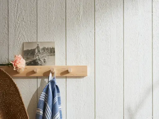 En träpanel inomhus inspiration med en ljus trähylla, en gammal bild, en blomma och en handduk.