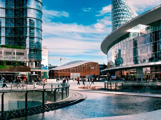 Scena urbana moderna con persone che passeggiano, un edificio IBM e grattacieli specchiati. Immagini di vita quotidiana in una città dinamica.