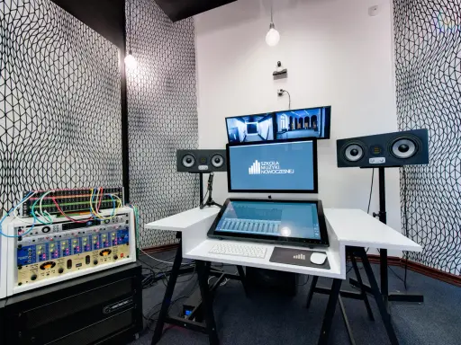 Profesjonalny komputer do muzyki w studiu nagraniowym, z monitorami studyjnymi i rackiem sprzętu audio.