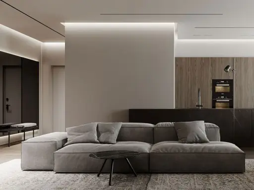 Soggiorno moderno con divano grigio, tavolino nero e cucina a vista. Un pilastro centrale, illuminato da luci a led, offre spunti su come abbellire un pilastro in soggiorno.