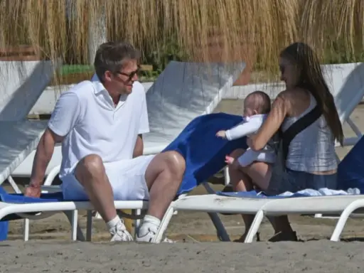 Hugh Grant njuter av stranden med sitt barn och en kvinna.