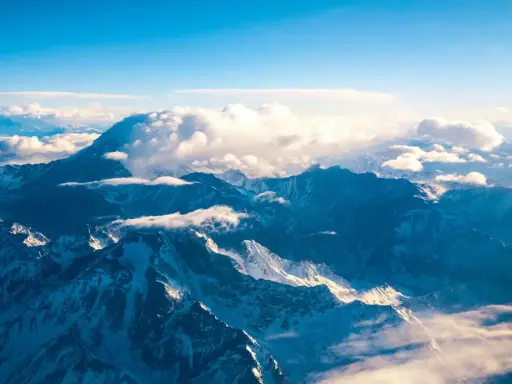Majestatyczne góry z Aconcagua, skąpane w słońcu, otoczone chmurami. Widok z lotu ptaka na ośnieżone szczyty.