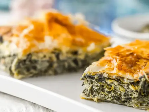 Chrupiąca spanakopita z warstwami ciasta filo i zielonym nadzieniem ze szpinaku i sera.