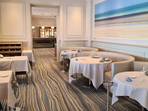 Élégant bistro à Saint-Malo, tables dressées, ambiance chic avec une fresque marine au mur.