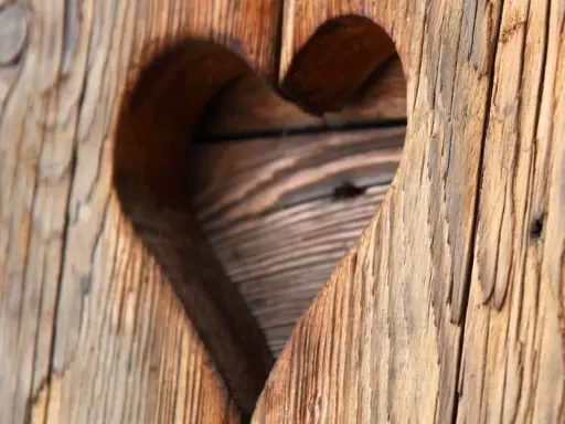 Corazón tallado en madera con textura de envejecer madera, mostrando vetas y grietas que cuentan historias.