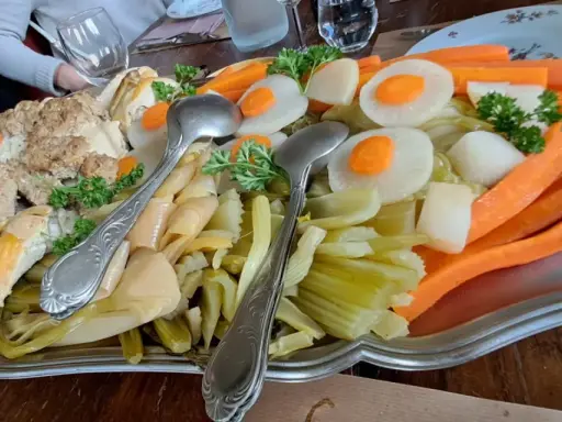 Plat généreux d'un restaurant du terroir : viandes, légumes racines et légumes verts, prêt à être dégusté.