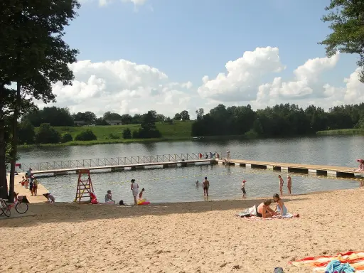 Słoneczny dzień na jednej z najpiękniejszych plaż na Mazurach. Ludzie odpoczywają na piaszczystym brzegu i w wodzie, ciesząc się latem.