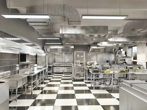 Cocina profesional de acero inoxidable con suelo de baldosas a cuadros, campanas extractoras y equipamiento listo para cualquier tipo de cocina.