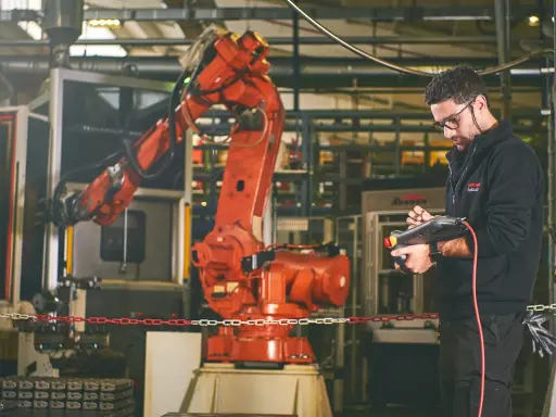 Un disegnatore meccanico opera un braccio robotico in una fabbrica. Il suo stipendio è ben meritato per la precisione richiesta.