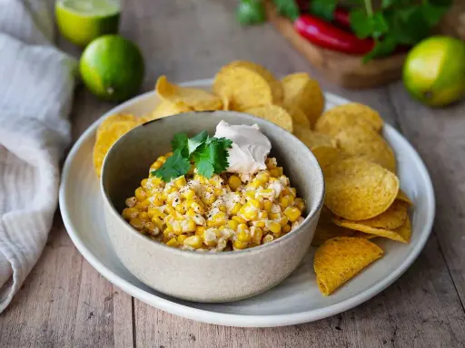 Krämig majsrätt med en klick gräddfil och koriander, serverad med tortillachips. Perfekt som tillbehör eller dipp.