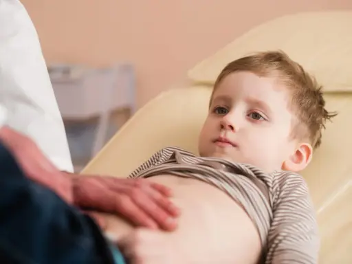 Un bambino viene visitato per sospetto neuroblastoma. Il medico gli tocca delicatamente l'addome.