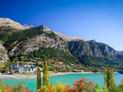 Pueblo de Lanuza, Huesca, con su embalse de aguas turquesas y montañas verdes.
