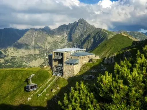 Górskie **kuźnice atrakcje** - kolejka linowa i schronisko na szczycie, otoczone majestatycznymi Tatrami.