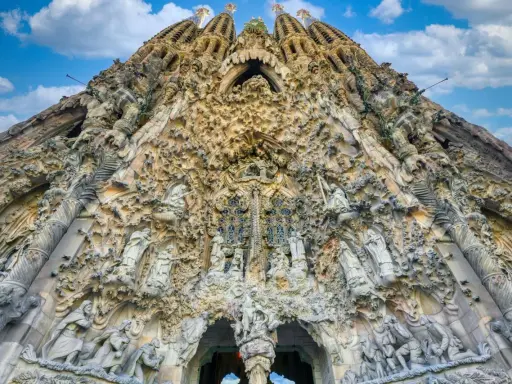 La Sagrada Familia, un capolavoro architettonico, si erge maestosa. La sua facciata è un tripudio di sculture, un racconto visivo che si estende dalla **distanza porto Barcellona Sagrada Familia**.