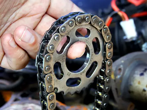 Wymiana rozrządu w Suzuki SX4 1.6 benzyna. Dłoń trzymająca koło zębate i łańcuch rozrządu.