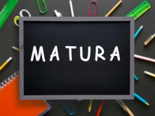 Czarna tablica z napisem "MATURA" kredą, otoczona przyborami szkolnymi. To symbol ważnego świadectwa dojrzałości.