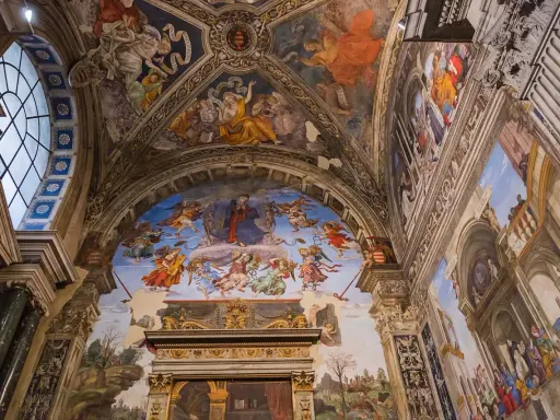Affreschi mozzafiato adornano le volte di chiese a Roma, raffiguranti scene celesti e figure bibliche con colori vibranti.