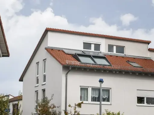 Ein Haus mit roten Ziegeln und Dachfenstern. Das Dach ist ein Pultdach, das nach einer Seite abfällt.