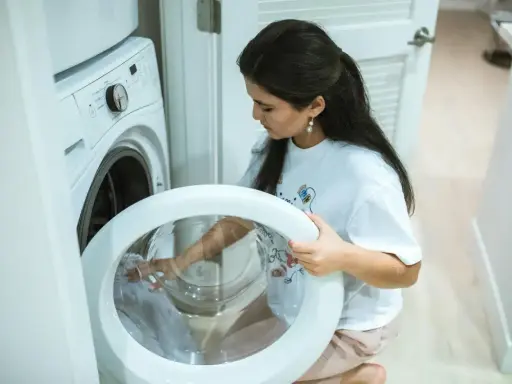 Une femme vérifie le tambour de sa machine à laver, craignant un siphon à machine à laver bouché.