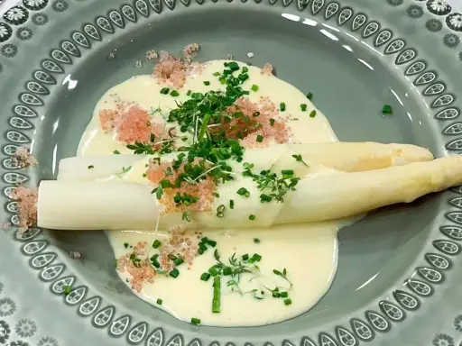 Vit sparris i en krämig sås till sparris, toppad med örter och rosa rom. En delikat rätt.