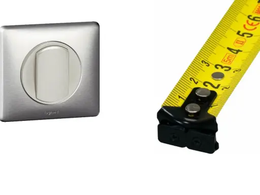 Interrupteur Legrand en métal brossé et mètre ruban jaune. Mesure de la hauteur interrupteur.