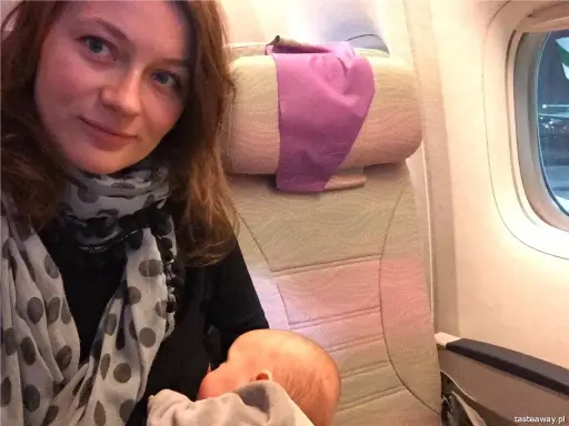 Kobieta karmi niemowlaka podczas lotu samolotem.