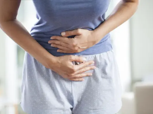 Kobieta trzyma się za brzuch, cierpiąc z powodu bólu menstruacyjnego nie do zniesienia.