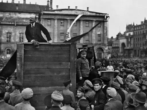Lenin spricht von einer improvisierten Bühne zu einer großen Menschenmenge. Die Szene wirkt wie eine "revolution von oben", die das Volk mobilisiert.
