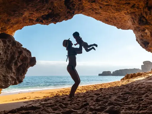 Madre levanta a su bebé en una cueva en el Algarve. Un día perfecto de algarve con niños.