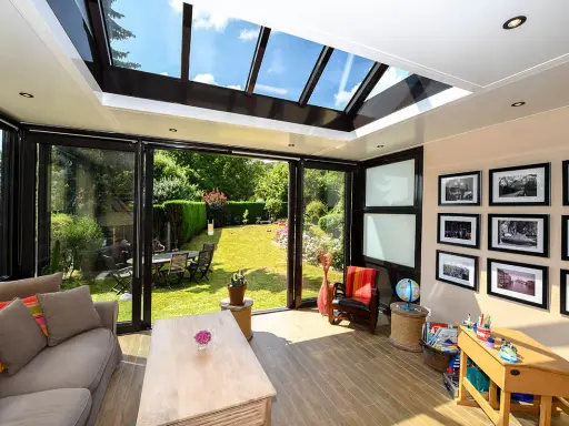 Un salon lumineux avec un canapé confortable, une table basse en bois, et une vue imprenable sur un jardin verdoyant depuis cette **veranda interieur**.