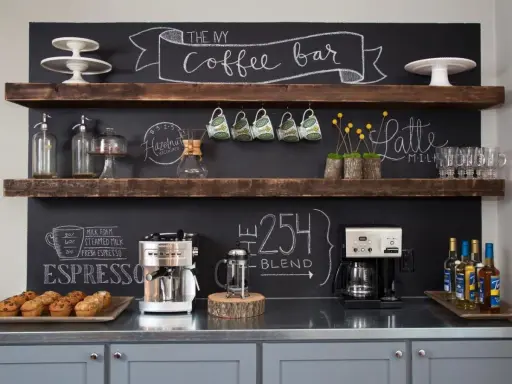 Un angolo caffè fai da te con macchine, tazze, muffin e scritte alla lavagna.