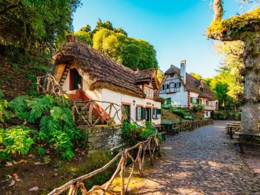 Casitas de cuento con tejados de paja, perfectas para crear viajes inolvidables para adolescentes. Un camino empedrado y vegetación exuberante.