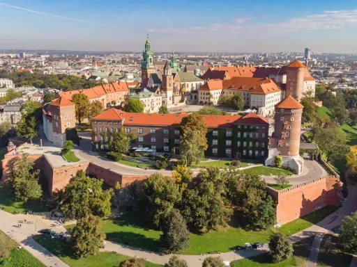Wawel w Krakowie, z charakterystyczną wieżą widokową, otoczony zielenią i zabytkową architekturą.