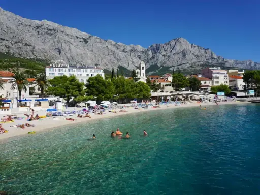 Słoneczna plaża w Baška Voda, z turkusową wodą i górami w tle. To idealne miejsce na relaks i odkrywanie atrakcji.