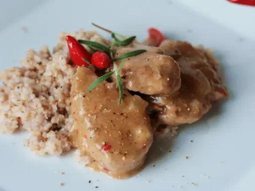 Polędwiczki wieprzowe w sosie własnym, danie Ani gotuje, podane z kaszą i ozdobione papryczką chili i rozmarynem.