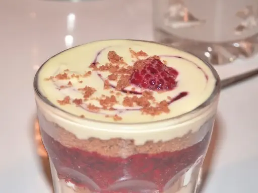 Verrine speculoos framboise : couches de biscuits émiettés, compotée de framboises et crème onctueuse, surmontée d'une framboise fraîche et miettes de spéculoos.