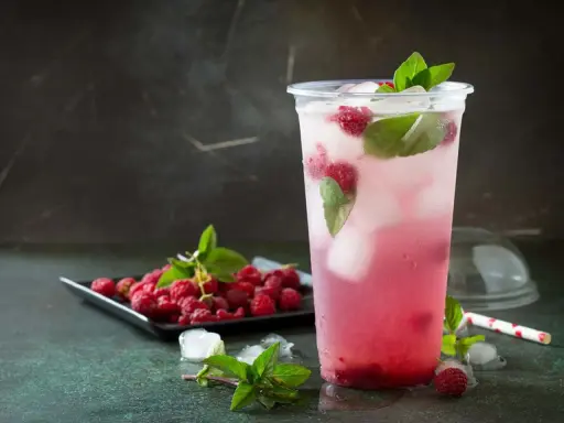En uppfriskande raspberry daiquiri med färska hallon och mynta, serverad i ett plastglas med is.